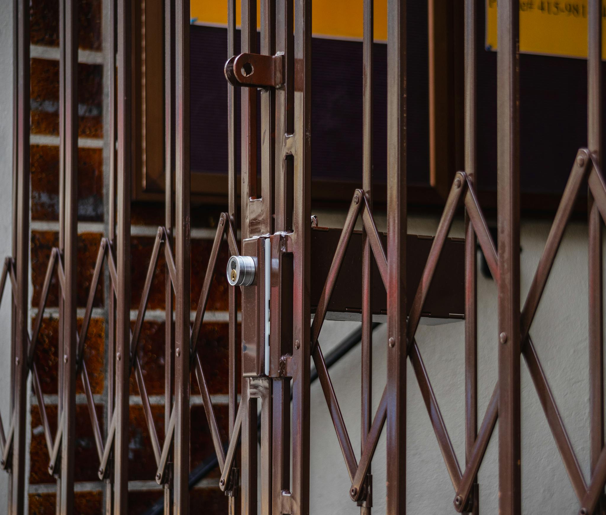 Close-up of a rusty folding metal gate with a lock, showing its design and texture.